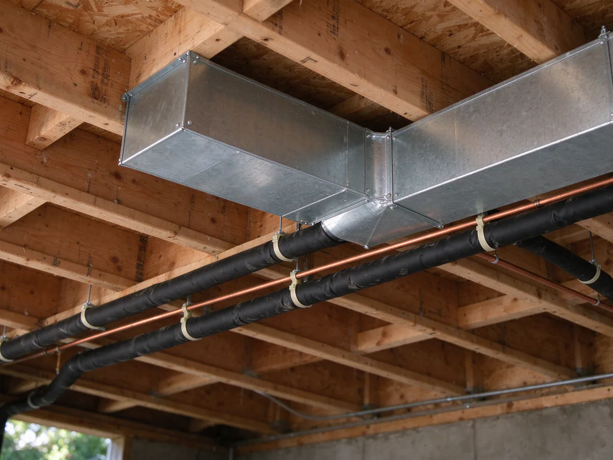 New refrigerant line set strapped along basement ceiling joists beside the duct trunk